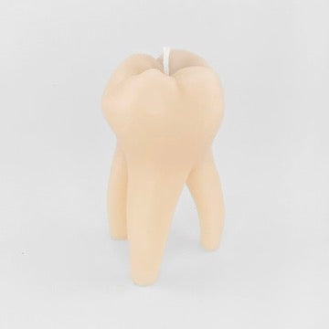 A novelty tooth-shaped candle in a realistic beige color, featuring a white wick at the top, set against a plain light gray background.
