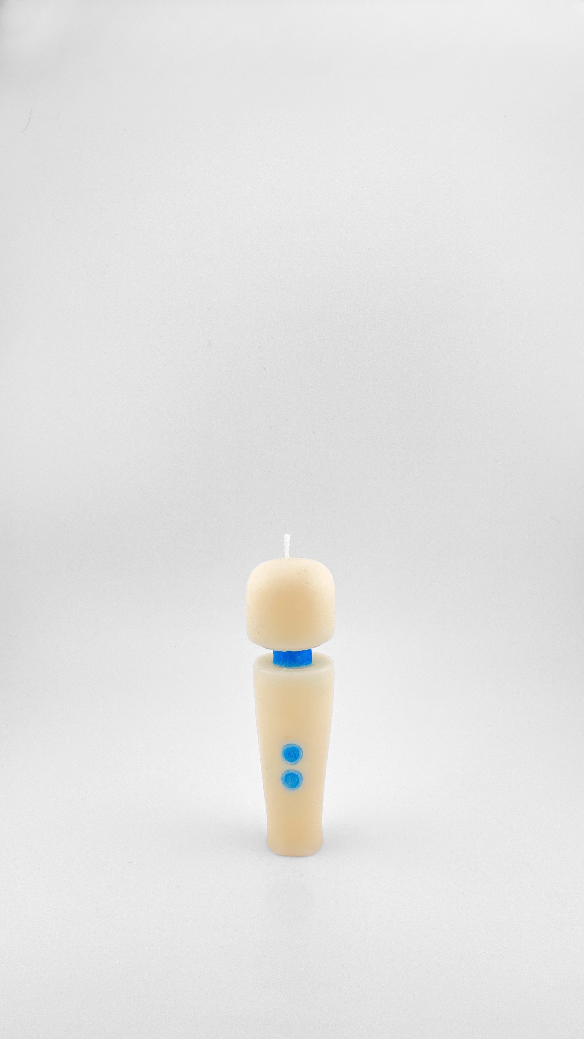 A small candle in off-white soy wax with a small blue collar and two blue buttons resembling the iconic Magic Wand Vibrator, standing on a white background.