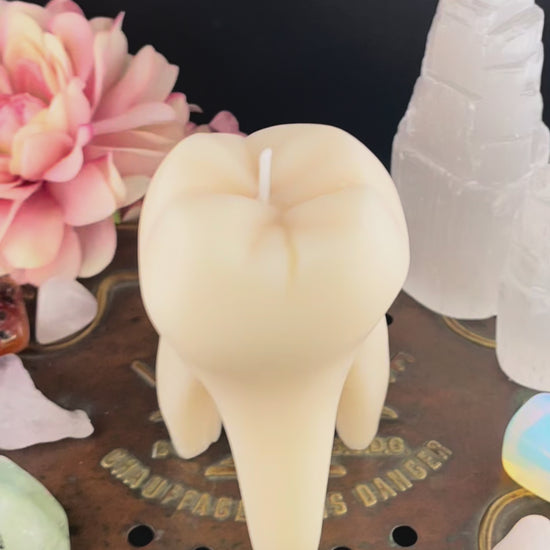 A time lapse video of a tooth candle melting and revealing a brass tag with hand-stamped text that reads "TRY ORGASM",